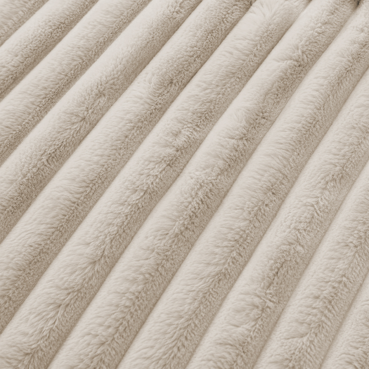 Détail du tissu en fourrure côtelée beige, reliefs verticaux et finition du velours.