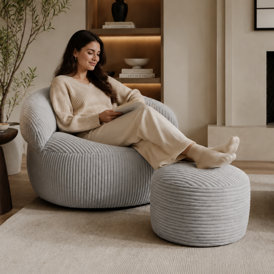 Personne assise confortablement sur un pouf XXL en velours côtelé avec repose-pieds, dans un salon