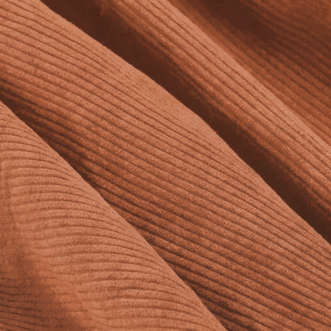 Gros plan du velours côtelé terracotta avec texture nervurée régulière.