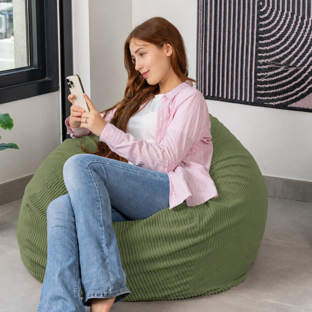 Femme assise sur un pouf poire déhoussable en velours côtelé, dans un salon