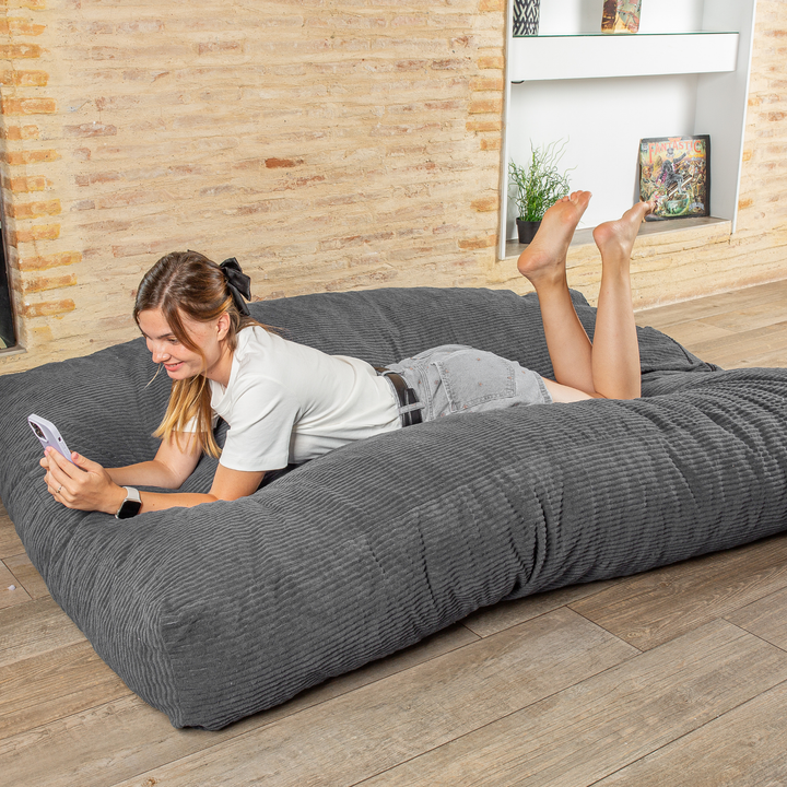 Personne allongée sur le pouf-lit convertible 2en1, utilisé en couchage pour se détendre