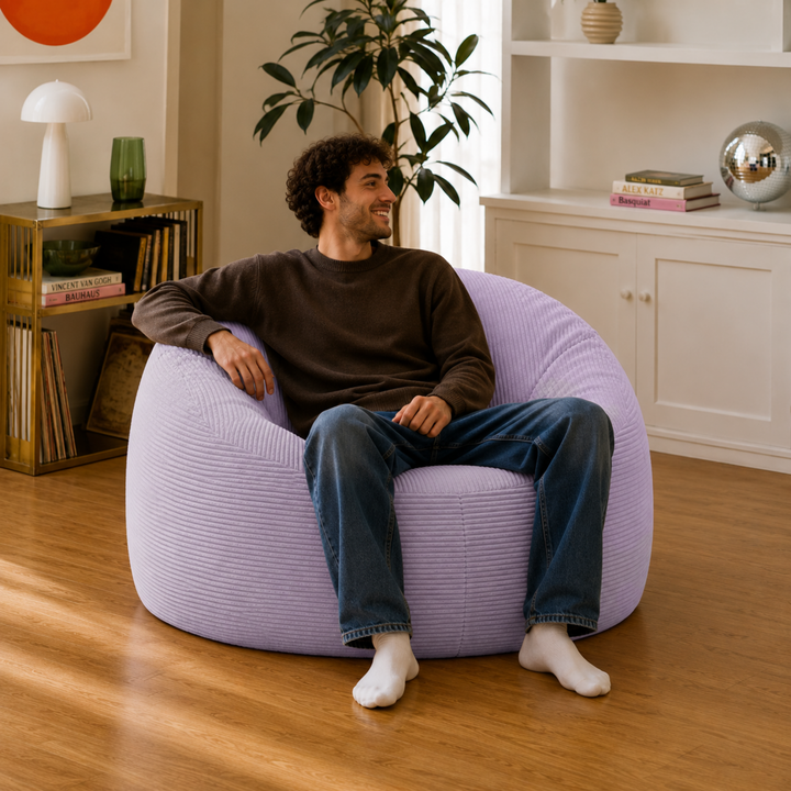 Homme assis sur un pouf déhoussable 100 cm en velours côtelé épais, violet.