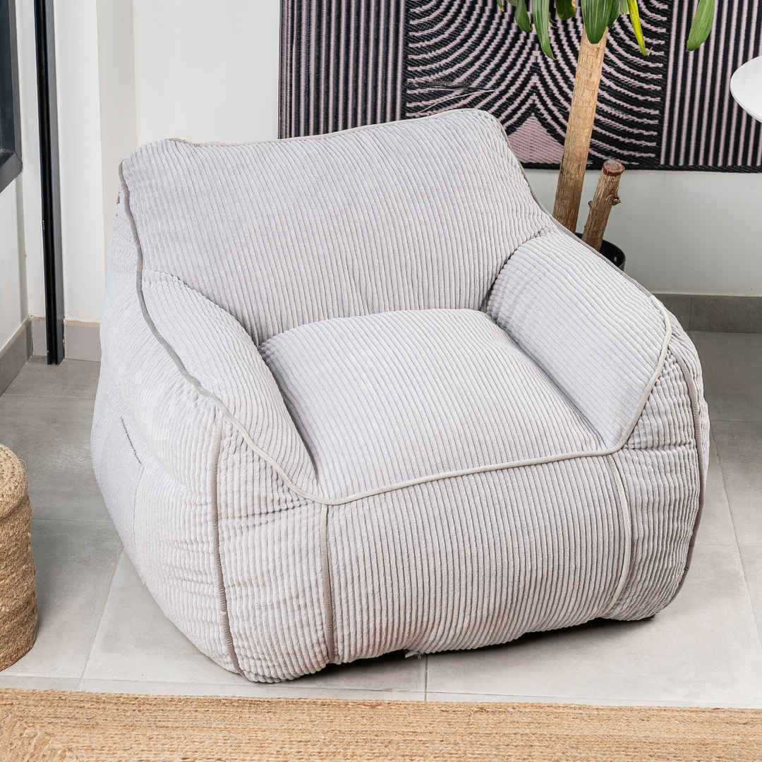 Pouf fauteuil velours côtelé gris clair, vue trois-quarts, dans un salon
