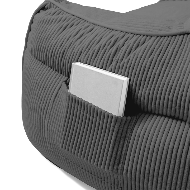 Pouf fauteuil en velours côtelé gris foncé, détail de la poche de rangement sur le côté.