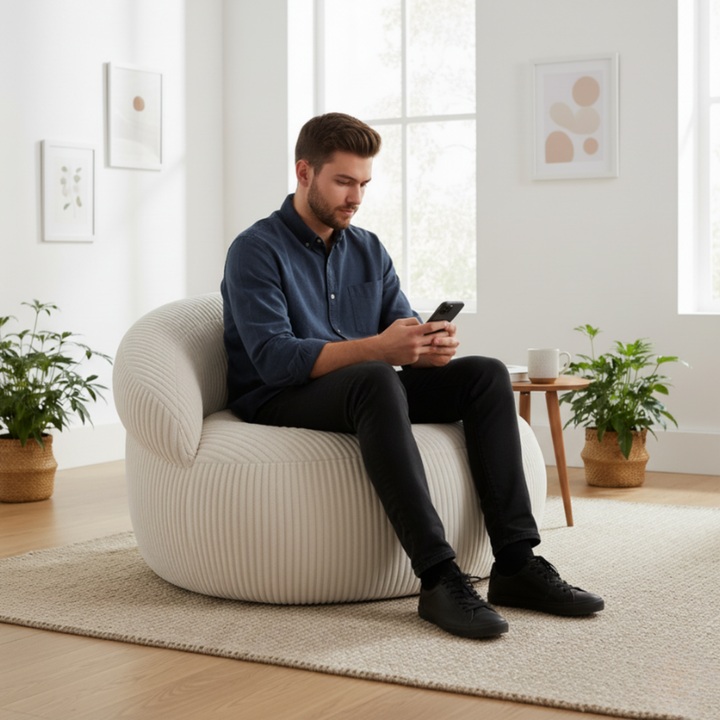 Personne assise sur un pouf XXL en velours côtelé, dans un salon