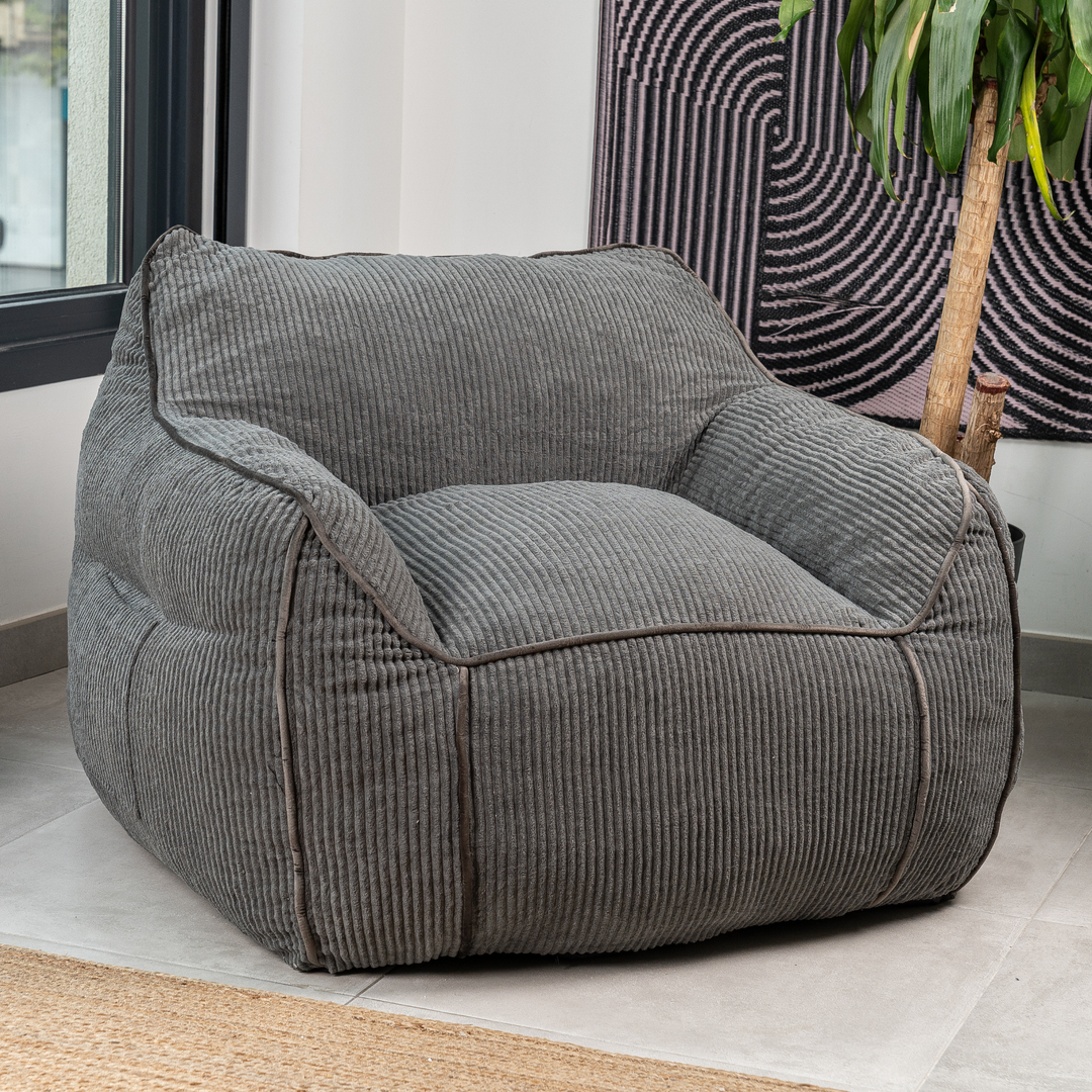 Pouf fauteuil en velours côtelé gris foncé, dans un salon